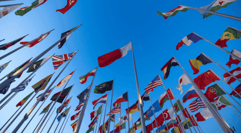 Varias banderas nacionales de diferentes países ondeando al viento con un cielo azul despejado de fondo. onhunters, firma de búsqueda y selección de personal.