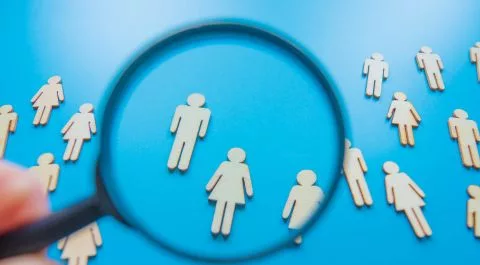 Figura humana vista a través de una lupa sobre fondo azul, simbolizando la búsqueda de talento. onhunters, firma de búsqueda y selección de personal.