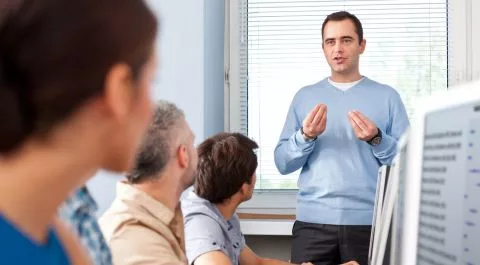 Formador explicando un proceso a un grupo de trabajadores logísticos en aula corporativa