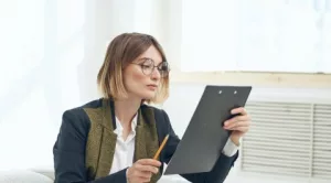 Mujer joven en proceso de evaluación de currículums, revisando detenidamente la información de un candidato.