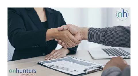 Primer plano de un apretón de manos en una entrevista profesional con documentos sobre la mesa. onhunters, firma de búsqueda y selección de personal.