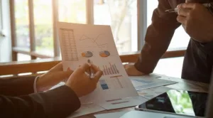 Dos profesionales de negocios analizando gráficos y datos en un informe para la toma de decisiones.